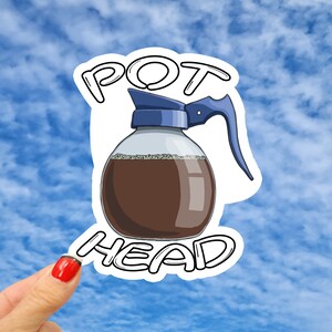 May include: A white sticker with a black outline of a coffee pot and the words "POT HEAD" in black.