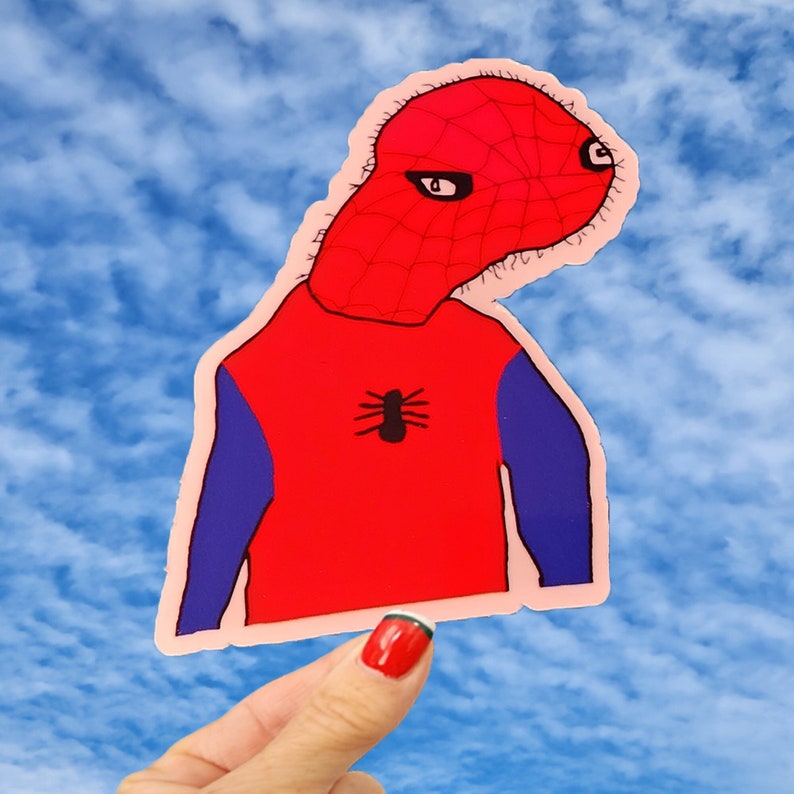 Puede incluir: Una pegatina roja y azul de un superh&eacute;roe de dibujos animados con un logotipo de ara&ntilde;a en el pecho. El superh&eacute;roe tiene una m&aacute;scara roja y negra en forma de telara&ntilde;a y lleva un traje rojo y azul.