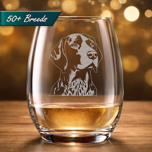May include: A stemless wine glass with a detailed etched portrait of a dog, filled with a golden liquid. The glass has the text "50+ Breeds" in a teal banner. The dog portrait is in shades of gray and white.