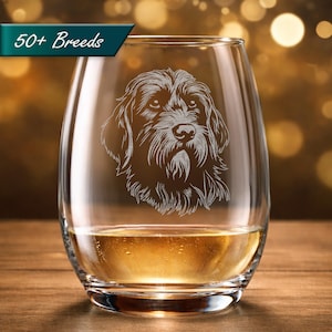 May include: A stemless wine glass with a detailed etched image of a dog's face. The glass is partially filled with a golden liquid. The text "50+ Breeds" is displayed on a teal banner in the upper left corner.