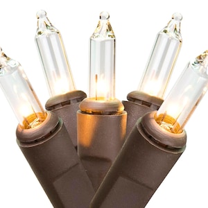 May include: A string of five clear incandescent light bulbs with brown plastic bases. Each bulb is cylindrical with a pointed tip, emitting a warm glow. The bulbs are connected by a brown wire, arranged in a cluster against a white background.
