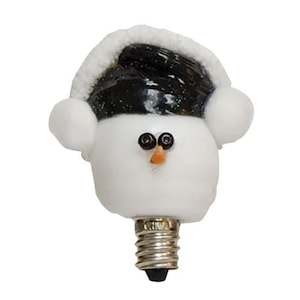 May include: A white snowman-shaped light bulb featuring a black hat with white trim and white earmuffs. The snowman has two small black bead eyes and a small orange carrot-shaped nose. The base is a standard metallic screw-in light bulb connector.