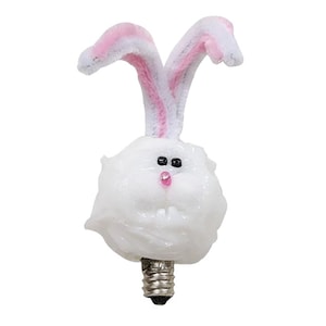 May include: White light bulb with a fluffy white bunny face and pink ears. The bunny has black eyes and a pink nose.