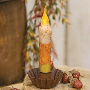 May include: A small, battery-operated candle with a yellow flame and a three-toned design of white, orange, and yellow. The candle is sitting in a brown metal candle holder with a fluted edge.