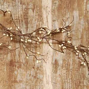 May include: A white berry garland with brown stems. The garland is draped over a rustic wooden surface.