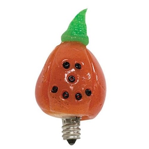 May include: Orange pumpkin shaped light bulb with a green stem and black eyes. The light bulb has a standard screw base.