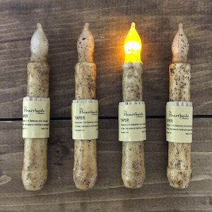 May include: Four battery-operated taper candles with a brown and white speckled finish. The candles are labeled "The Hearthside Collection" and "TAPER" and require 2 AA batteries (not included).