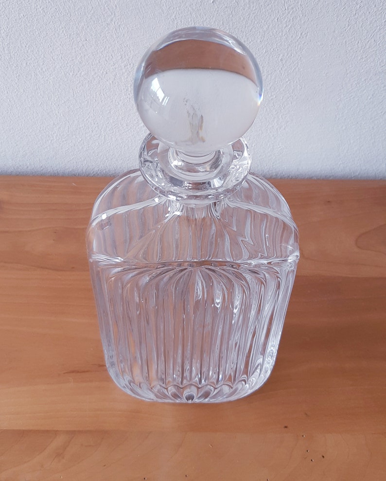 Puede incluir: Una decantador de vidrio transparente con un tap&oacute;n redondo. La decantador tiene un dise&ntilde;o texturizado y acanalado.