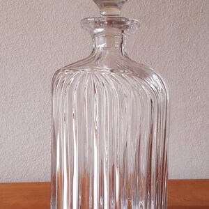 Puede incluir: Una decantador de vidrio transparente con un dise&ntilde;o acanalado y un tap&oacute;n redondo. La decantador est&aacute; vac&iacute;a y tiene un acabado pulido.