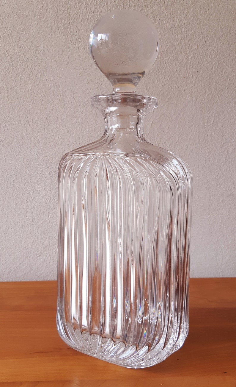 Puede incluir: Una decantador de vidrio transparente con un dise&ntilde;o acanalado y un tap&oacute;n redondo. La decantador est&aacute; vac&iacute;a y tiene un acabado pulido.