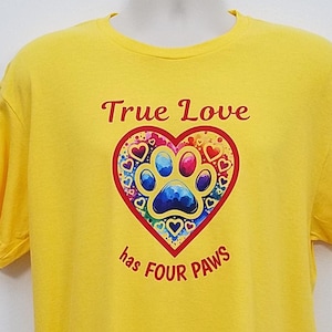 May include: A yellow t-shirt featuring the text "True Love has FOUR PAWS" in red. The design includes a heart-shaped graphic with a paw print and hearts in various colors. The shirt is displayed on a mannequin.