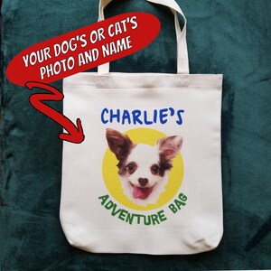 May include: White canvas tote bag with a yellow circle and a photo of a dog with the text "CHARLIE'S ADVENTURE BAG" printed on it.