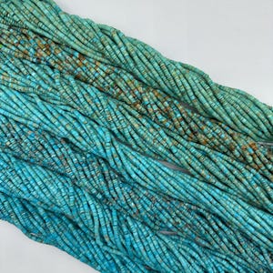 May include: A strand of turquoise beads, each bead is a light blue color with brown and white marbling. The beads are round and have a smooth, polished finish.