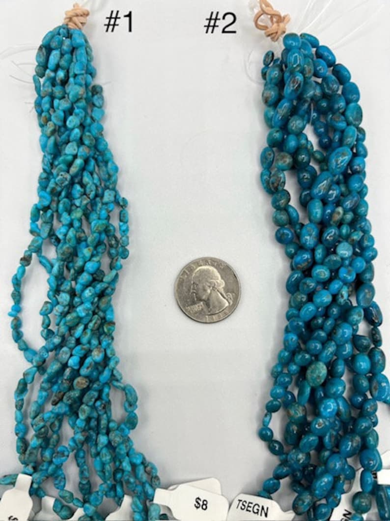 May include: Two strands of turquoise beads, one with small, irregular shaped beads and the other with larger, oval shaped beads. The strands are labelled #1 and #2.