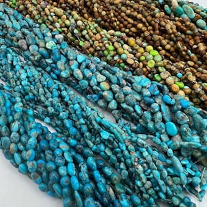 May include: A collection of turquoise gemstone beads in various shades of blue, green, and brown. The beads are all irregular in shape and have a natural, rough texture.