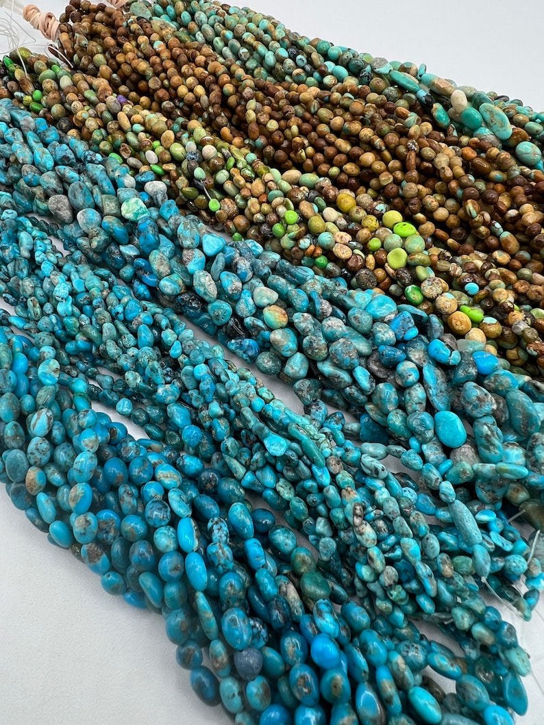 May include: A collection of turquoise gemstone beads in various shades of blue, green, and brown. The beads are all irregular in shape and have a natural, rough texture.