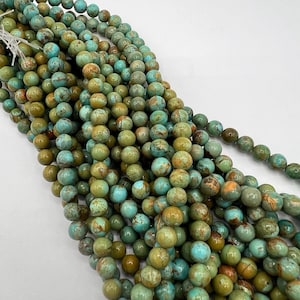 May include: A strand of turquoise-colored beads with brown and green marbling. The beads are round and smooth, and they are strung together on a clear thread.