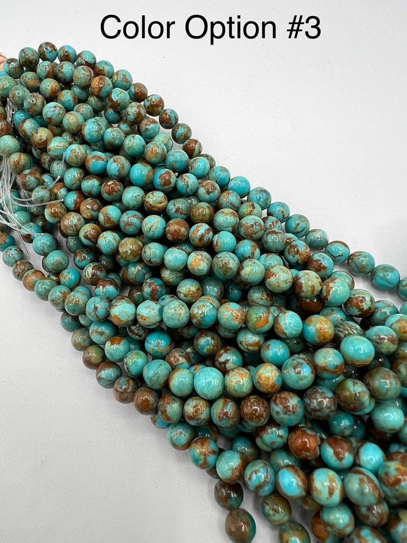 May include: A strand of turquoise blue and brown round beads. The beads have a marbled pattern and are arranged in a pile.