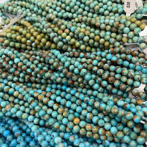 May include: A close-up of a strand of turquoise beads. The beads are a mix of blue and green with brown speckles. The beads are round and smooth. The price tag reads $28.