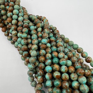 May include: A strand of turquoise blue and brown round beads. The beads have a marbled pattern and are strung together on a clear thread.