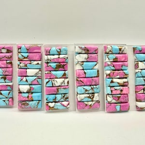 May include: Six stacks of rectangular gemstone beads in shades of pink, blue, white, and gold. The beads are arranged in clear plastic packaging, showcasing the colorful, patterned stones. Ideal for jewelry making.