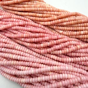 May include: Multiple strands of small, round, disc-shaped beads in varying shades of soft pink and peach. The beads are arranged in parallel rows, showcasing a smooth, uniform texture and a consistent size across each individual strand of jewelry.