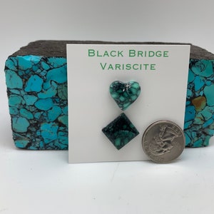 May include: A set of two green variscite cabochons, one heart-shaped and one square, on a white card with the text "Black Bridge Variscite". A US quarter is included for scale.