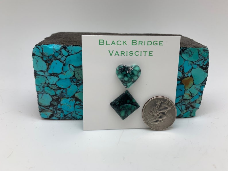May include: A set of two green variscite cabochons, one heart-shaped and one square, on a white card with the text "Black Bridge Variscite". A US quarter is included for scale.