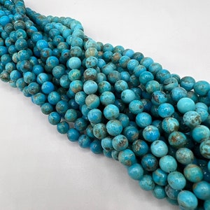 May include: A strand of turquoise blue beads with brown and white marbling. The beads are round and have a smooth, polished finish.