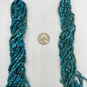 May include: Two strands of turquoise beads, each about 18 inches long, are displayed next to a US quarter for size comparison. The beads are a light blue color with brown flecks and have a slightly irregular shape.