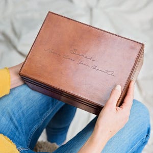 May include: A brown leather box with a personalized inscription that reads "To Sarah, Never Lose Your Sparkle".