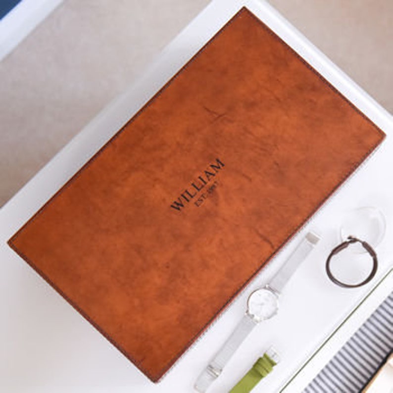 May include: A brown leather box with the text "WILLIAM EST. 1997" embossed on the top.