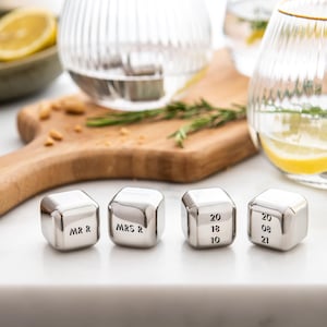 May include: Four stainless steel ice cubes with engraved text. Two cubes read "MR R" and "MRS R". The other two cubes have numbers engraved on them: "20 18 13 10" and "20 08 21".