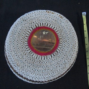 May include: A round, white beaded mirror with a red and gold trim around the mirror. The mirror is about 7 inches in diameter.