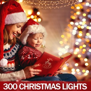 May include: A mother and child wearing Santa hats read a book together in front of a Christmas tree with white lights. The text "300 Christmas Lights" is at the bottom of the image.