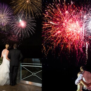 May include: A couple watches a fireworks display at night. The bride is wearing a white wedding dress and the groom is wearing a black suit. The fireworks are in the background and are red, white, and blue.