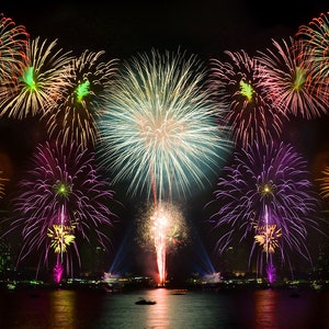 May include: A colorful fireworks display over a body of water. The fireworks are exploding in the night sky, creating a variety of shapes and colors. The water is reflecting the light from the fireworks.