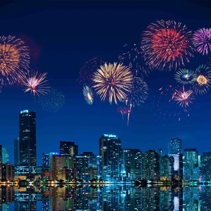 May include: A nighttime cityscape with colorful fireworks exploding in the sky. The fireworks display features red, yellow, and purple bursts above the illuminated buildings. The city lights reflect in the water below.