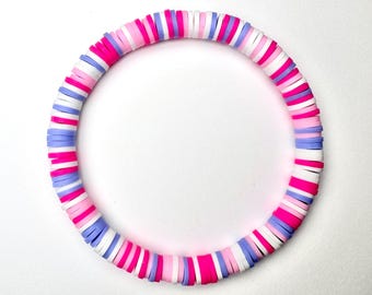 May include: A colorful bracelet made of stacked, round, polymer clay beads. The beads are pink, white, and lavender.