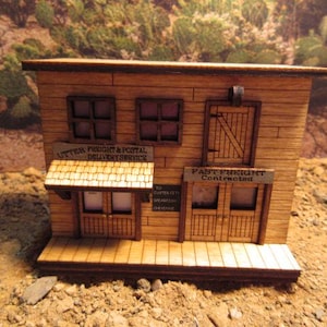 May include: A wooden model of a two-story building with a sign that reads "Utter Freight & Postal Delivery Service". The building has two windows on the top floor and a door on the bottom floor. The sign "Fast Freight Contracted" is on the lower level.