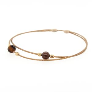May include: A brown and gold bracelet with two beads. The bracelet is made of a thin, brown cord and has two beads, one brown and one tiger's eye.