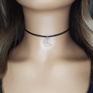 May include: A black choker necklace with a silver crescent moon charm with a small star in the center.