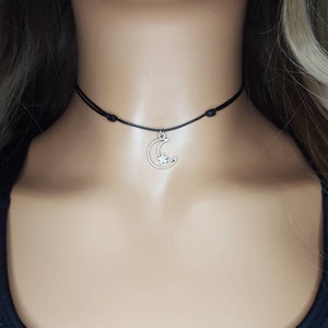 May include: A black choker necklace with a silver crescent moon charm featuring a small star inside.
