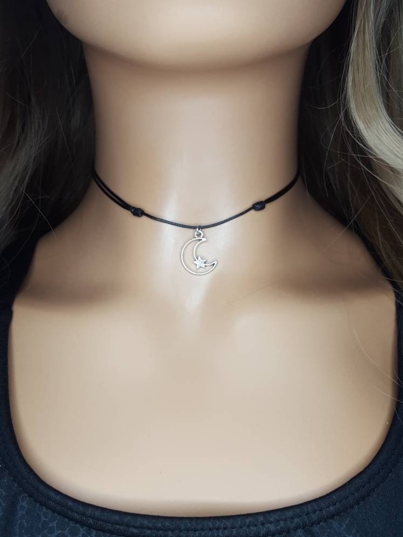 May include: A black choker necklace with a silver crescent moon charm featuring a small star inside.