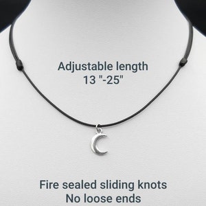 May include: A silver crescent moon pendant necklace on a black adjustable cord. The cord is 13 to 25 inches long and has fire-sealed sliding knots.  The necklace has no loose ends.