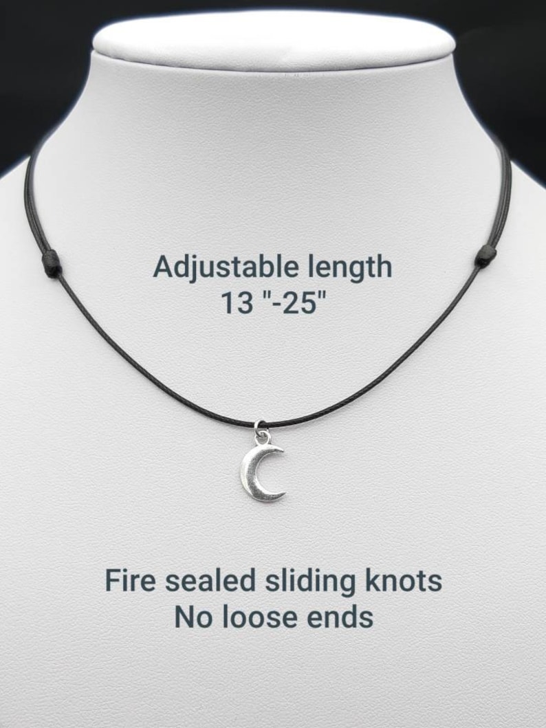 May include: A silver crescent moon pendant necklace on a black adjustable cord. The cord is 13 to 25 inches long and has fire-sealed sliding knots.  The necklace has no loose ends.