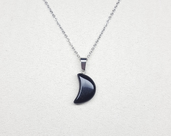 May include: A silver chain necklace with a black crescent moon pendant.