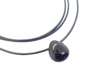 May include: A black gemstone pendant on a black cord necklace. The pendant is shaped like a teardrop.