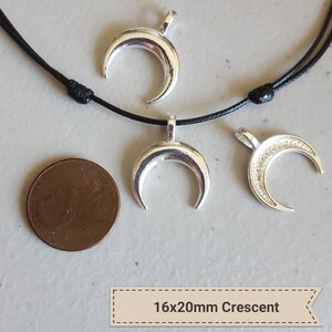 May include: Three silver crescent moon charms on a black cord necklace. The charms are 16mm by 20mm in size.