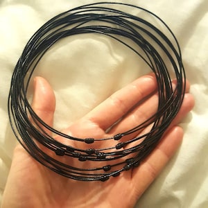 May include: A stack of black cord necklaces with small black beads at the ends.